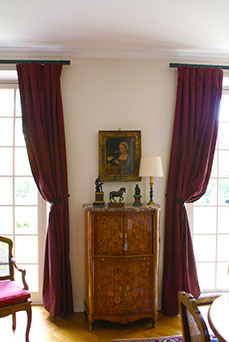 Le mur entre les deux rideaux de taffeta rouge est recouvert s'un tissu ivoire de chez Nobilis. 