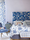 Tête de lit boutonnée recouverte d'un tissu à fleur Jane Churchill bleu et blanc, cache sommier bleu coordonné.